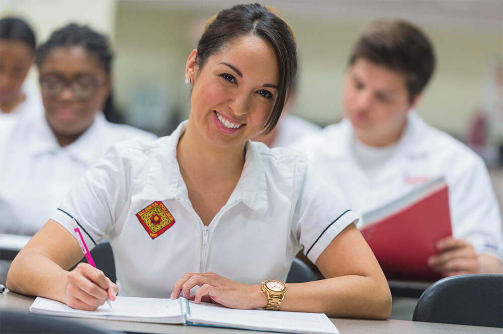 Nursing student with pen and notebook taking notes at desk
