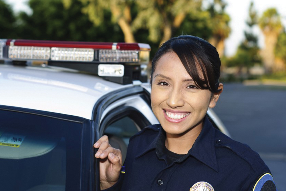 Criminal Justice female officer smiling near police car