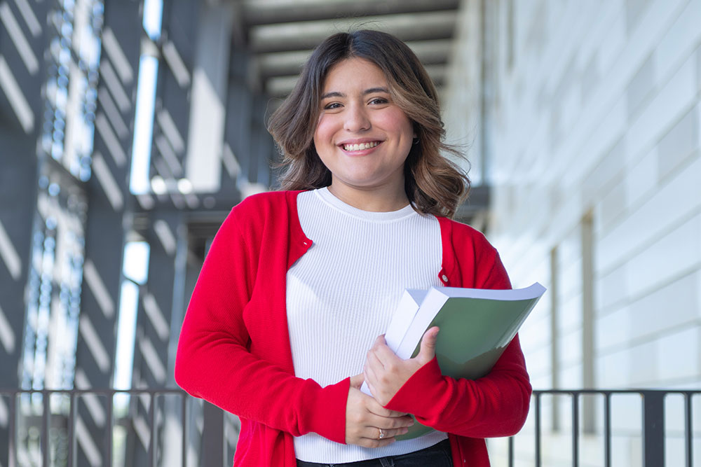 Portrait of female student holding book - Networking Engineering Technology program