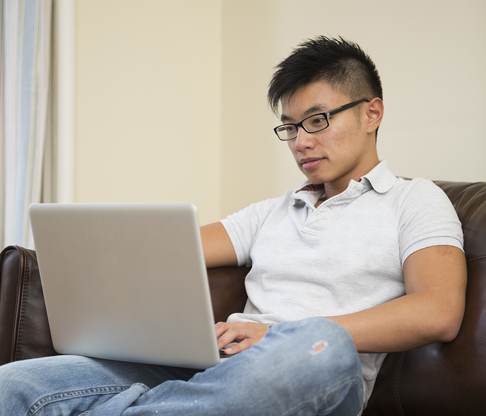 Male student using laptop to access account at home